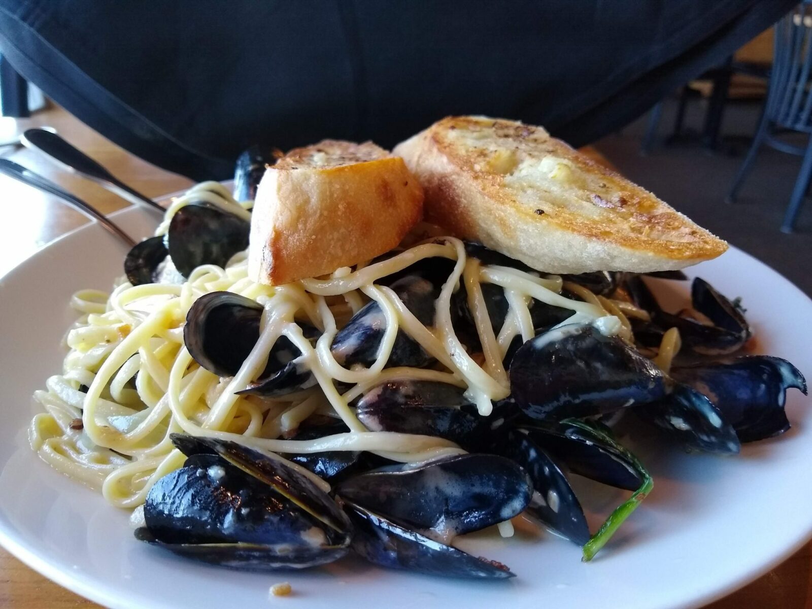 A plate of Penn Cove mussels with pasta and bread on top