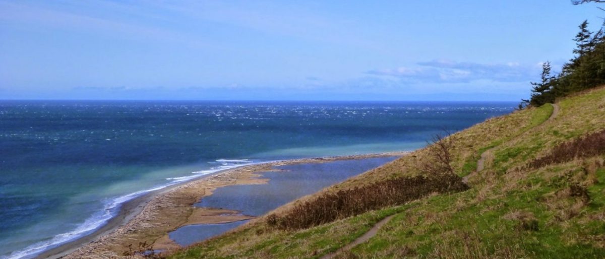Trail on a hillside above a lagoon and water on a sunny day