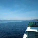 part of a ferry boat and the shoreline on a sunny day