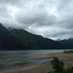 A sandy beach on an overcast day with forested hills in the background