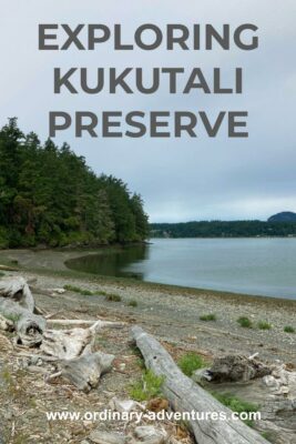 A beach with driftwood and forest alongside. In the distance is other forested land. Text reads: Exploring Kukutali Preserve