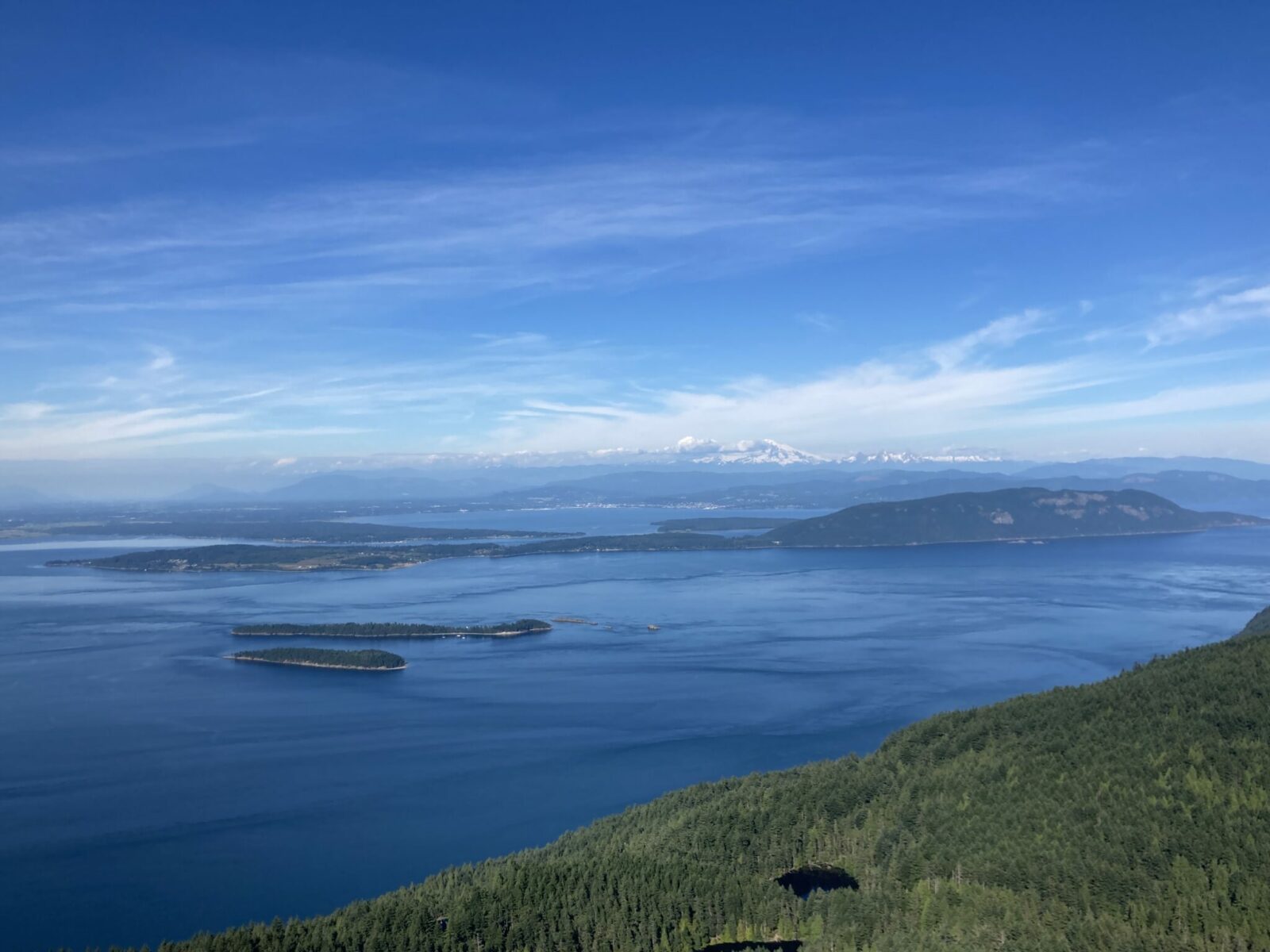 Distant mountains, islands and ocean with forest and lakes in the foreground from Mt Consitution on Orcas Island