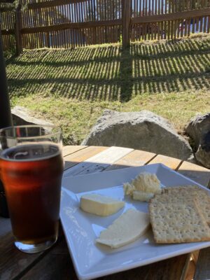 A beer in a glass next to a plate of crackers and cheese at island hoppin' brewery, one of the best things to do on orcas island