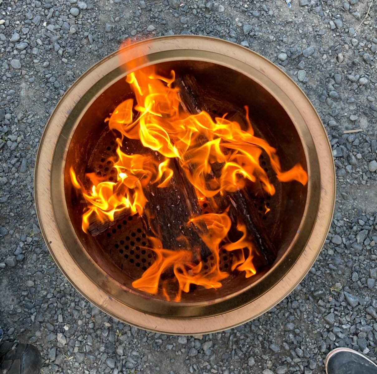 A top down view of a fire in a smokeless fire pit. The fire pit is sitting on gravel.