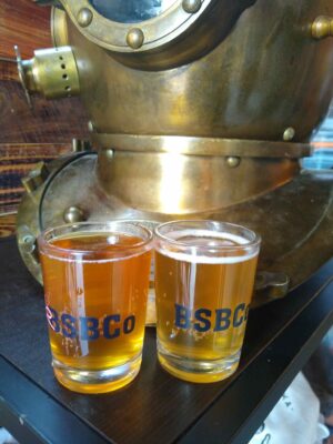 Two small beer tasting glasses filled with beer with the initials BSBC, one of the breweries in Alaska