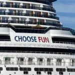 the stern of a cruise ship with many balconies. A blue and red sign says "choose fun"
