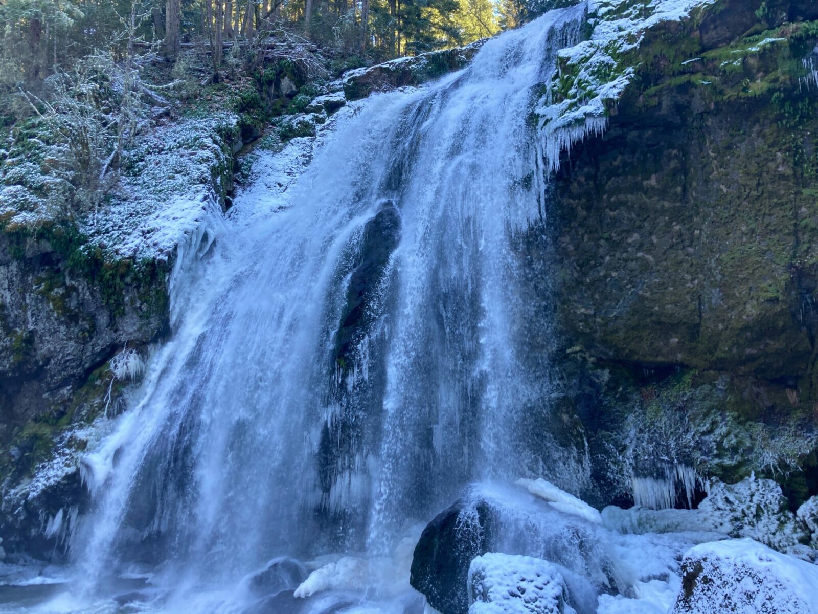 Partially frozen little mashel falls surrounded by forest on a winter day