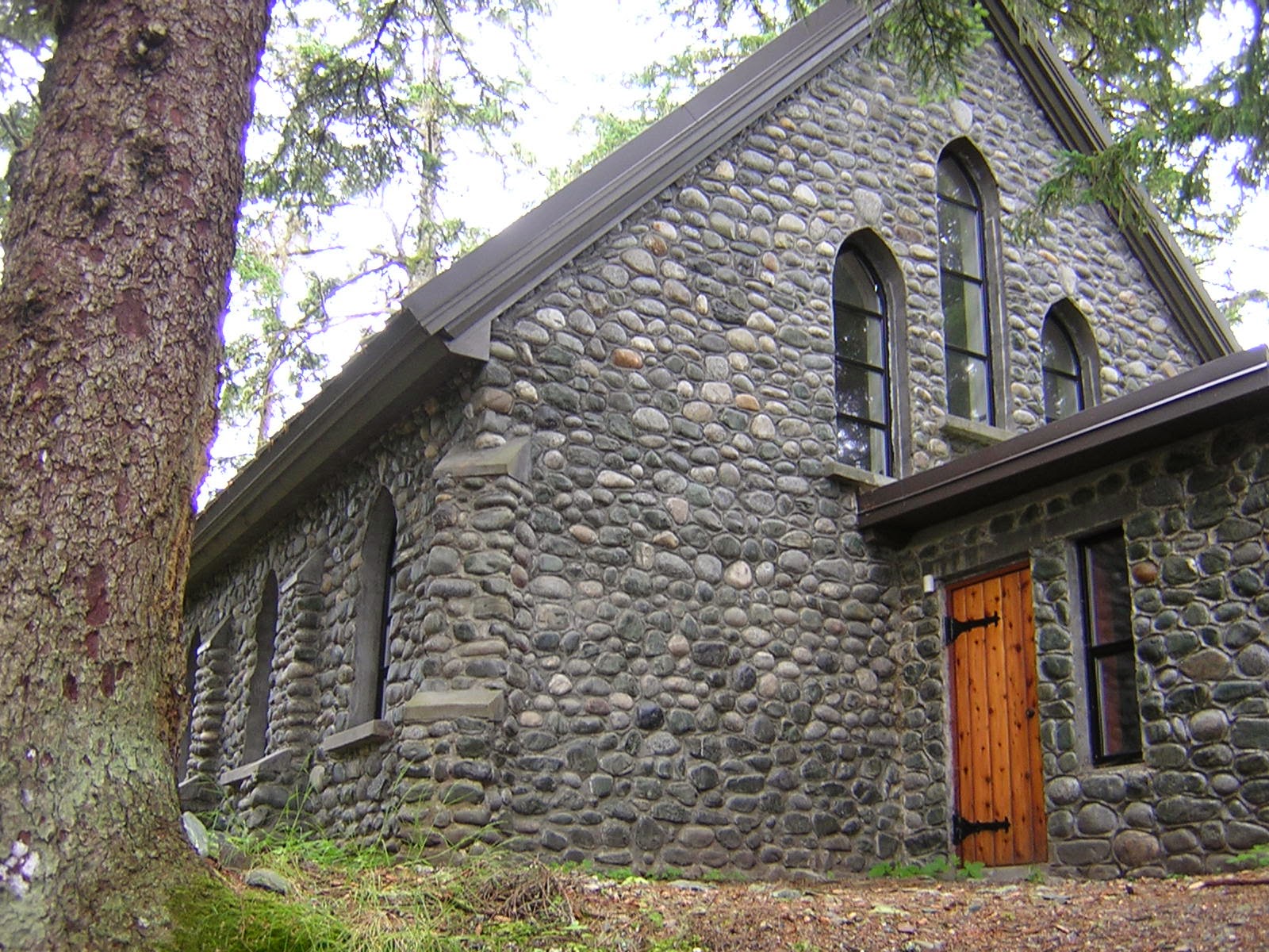 A stone chapel with a large tree next to it