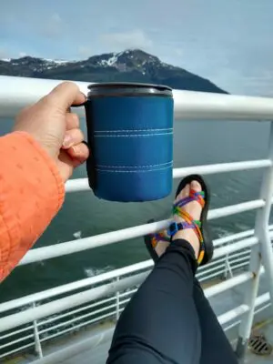 A person sitting on the deck of a ship holding a coffee cup