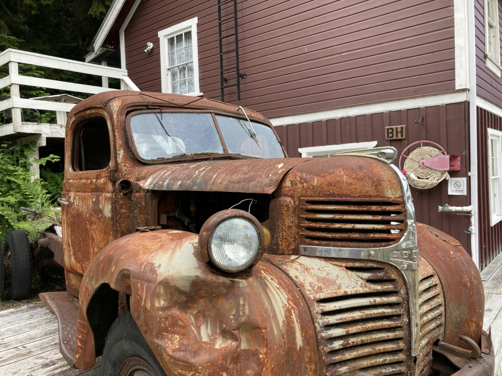 An old rusty truck on a wooden boardwalk in front of a wooden building