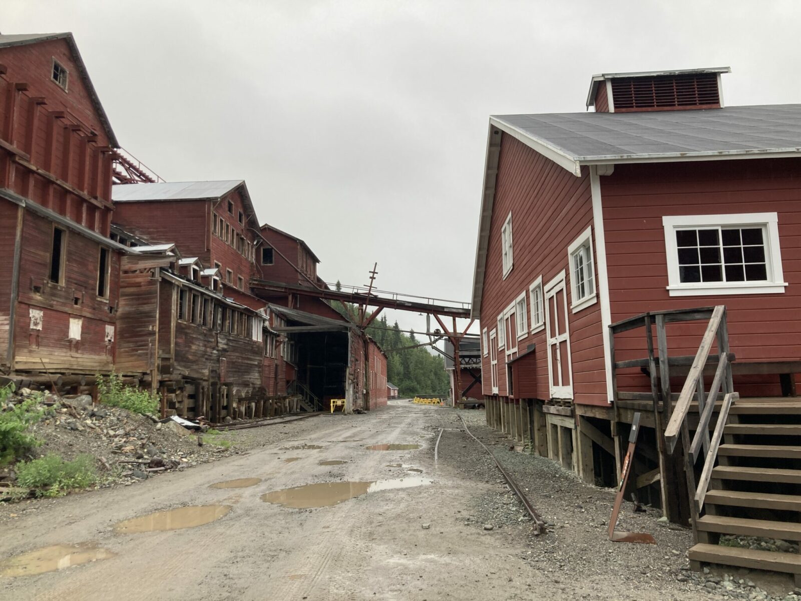 Red historic mining buildings on both sides of a muddy dirt road