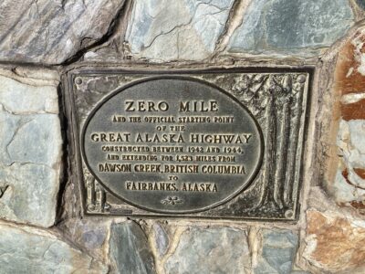 A stone monument with a metal plaque reading Zero Mile and the official starting point of the Great Alaska highway constructed between 1942 and 1944, and extending 1523 miles from Dawson Creek British Columbia to Fairbanks Alaska.