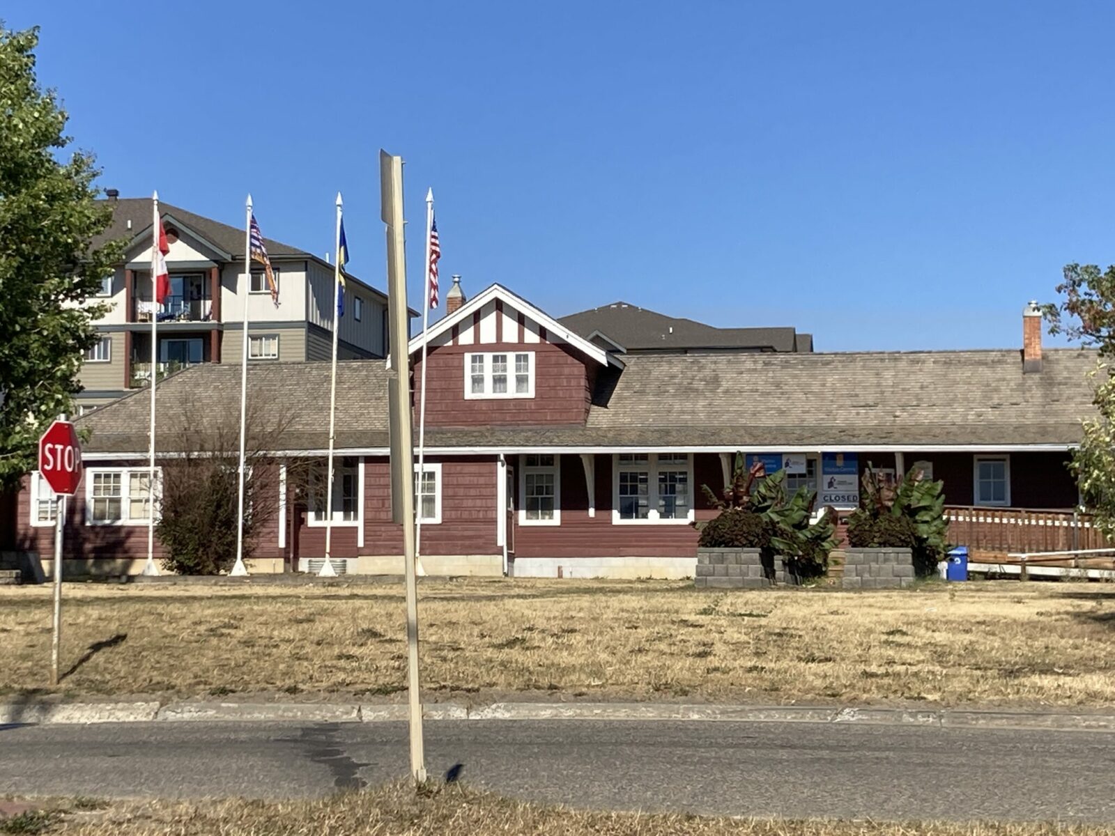 A historic train station operator building that is now a museum. It is a red building with white trim with several flags in front.