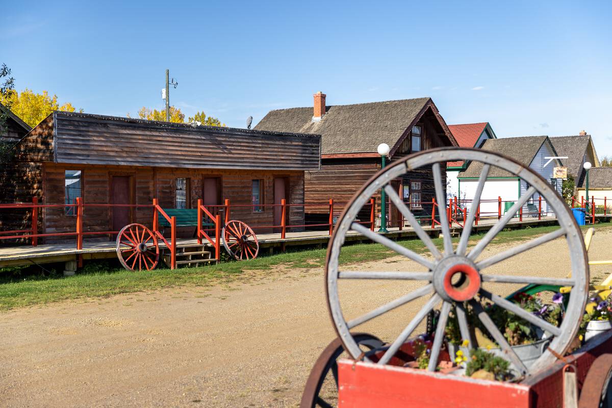 A dirt street with wooden boardwalks on both sides and red railings. Historic wooden buildings are along the boardwalk