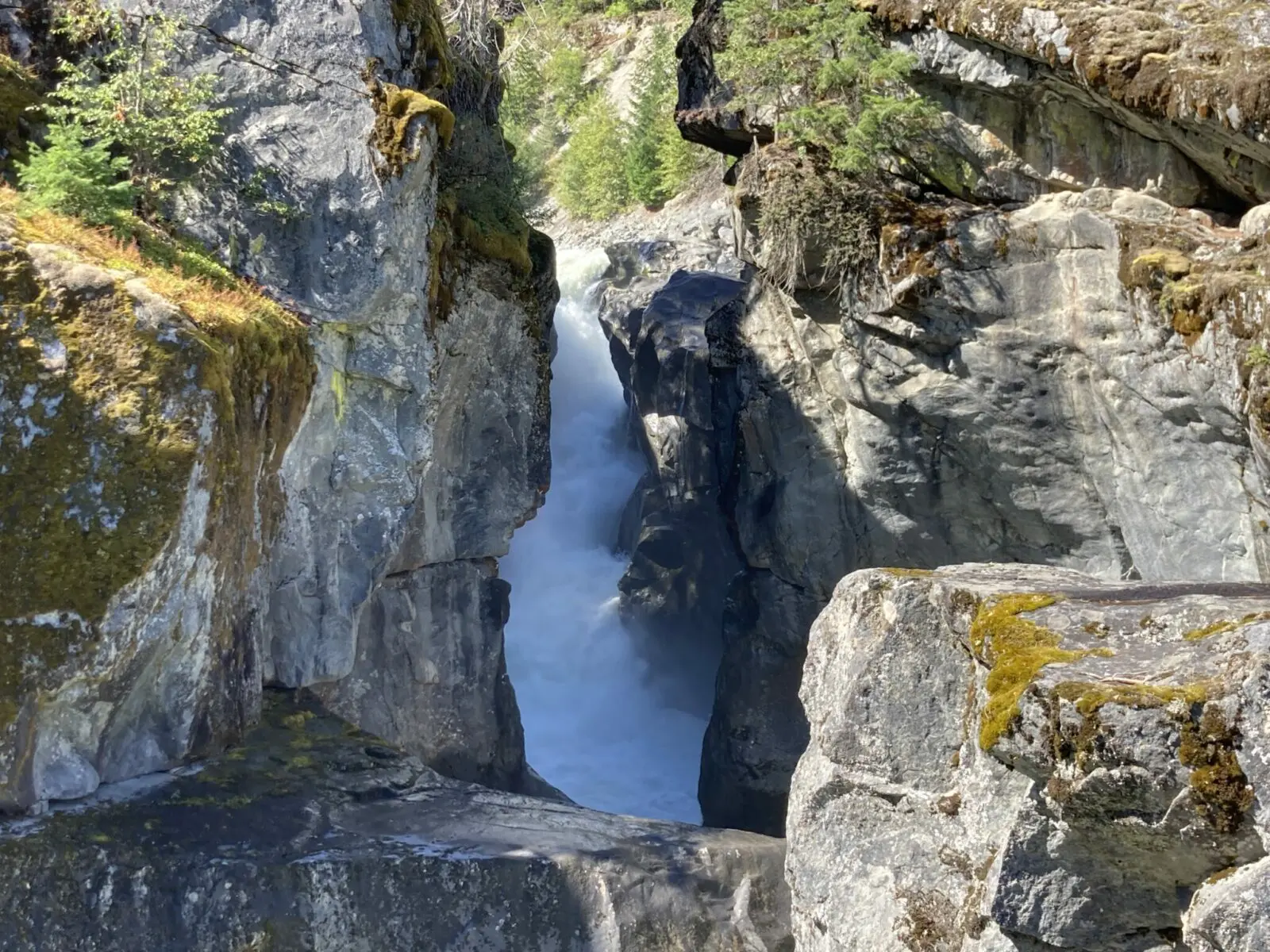 A narrow steep waterfall in a rocky canyon