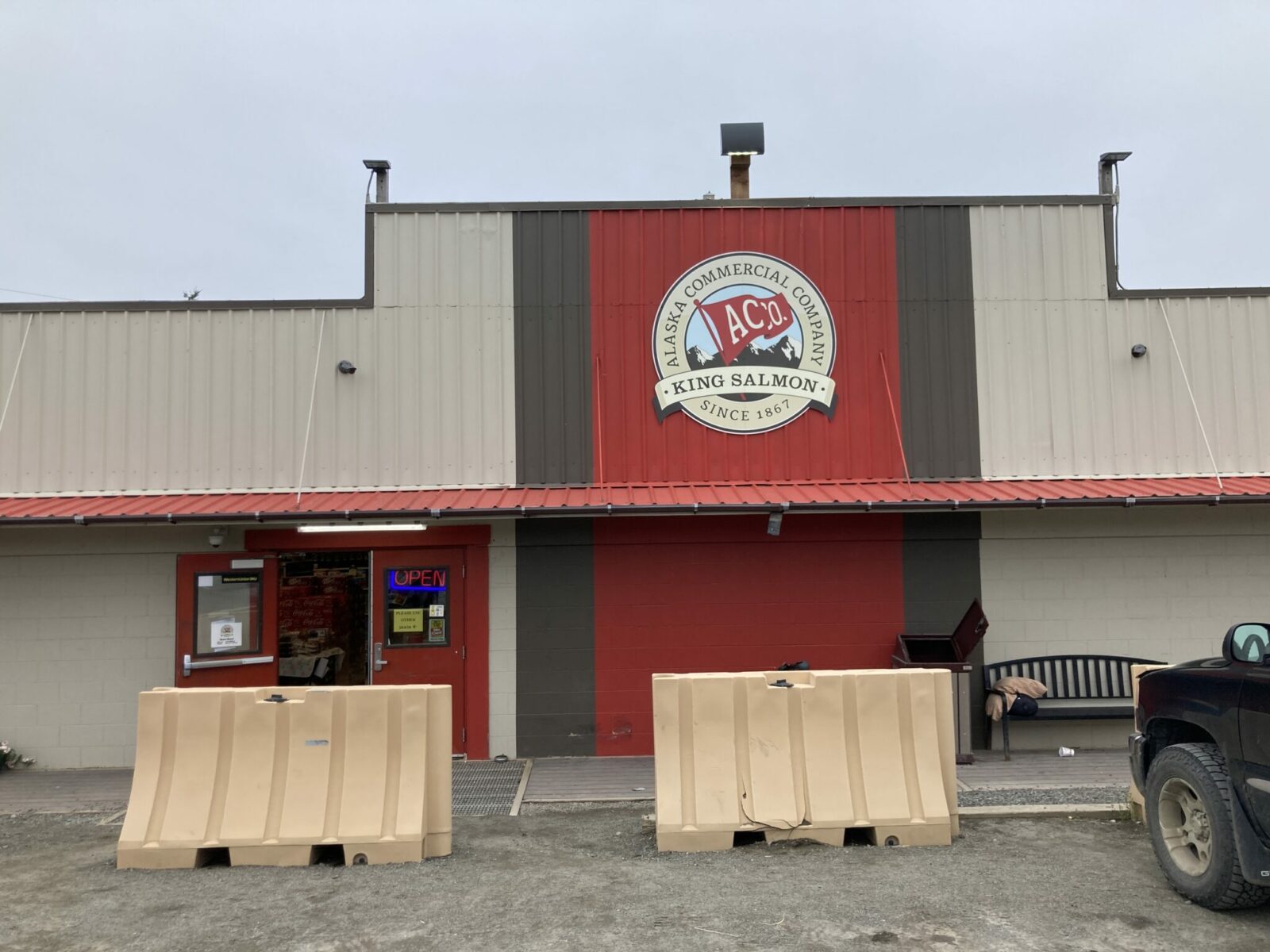 A brown and red building with a truck parked in front. The sign says Alaska Commercial Company King Salmon.