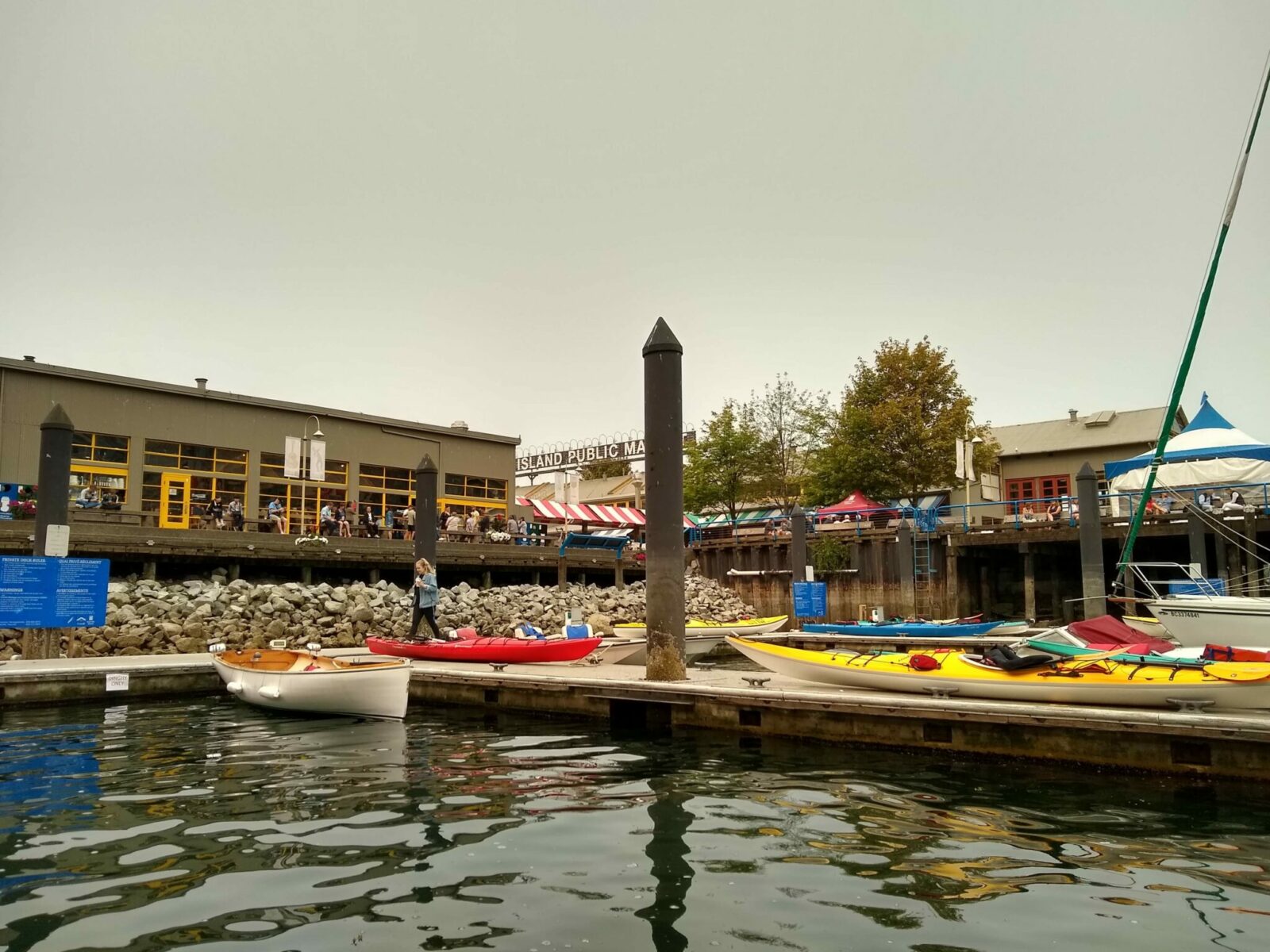 Several yellow and red kayaks on docks next to a breakwater at Granville Island in Vancouver BC