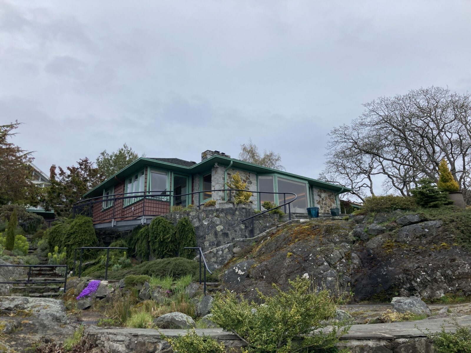 A wooden and stone building with windows seen from the garden below it