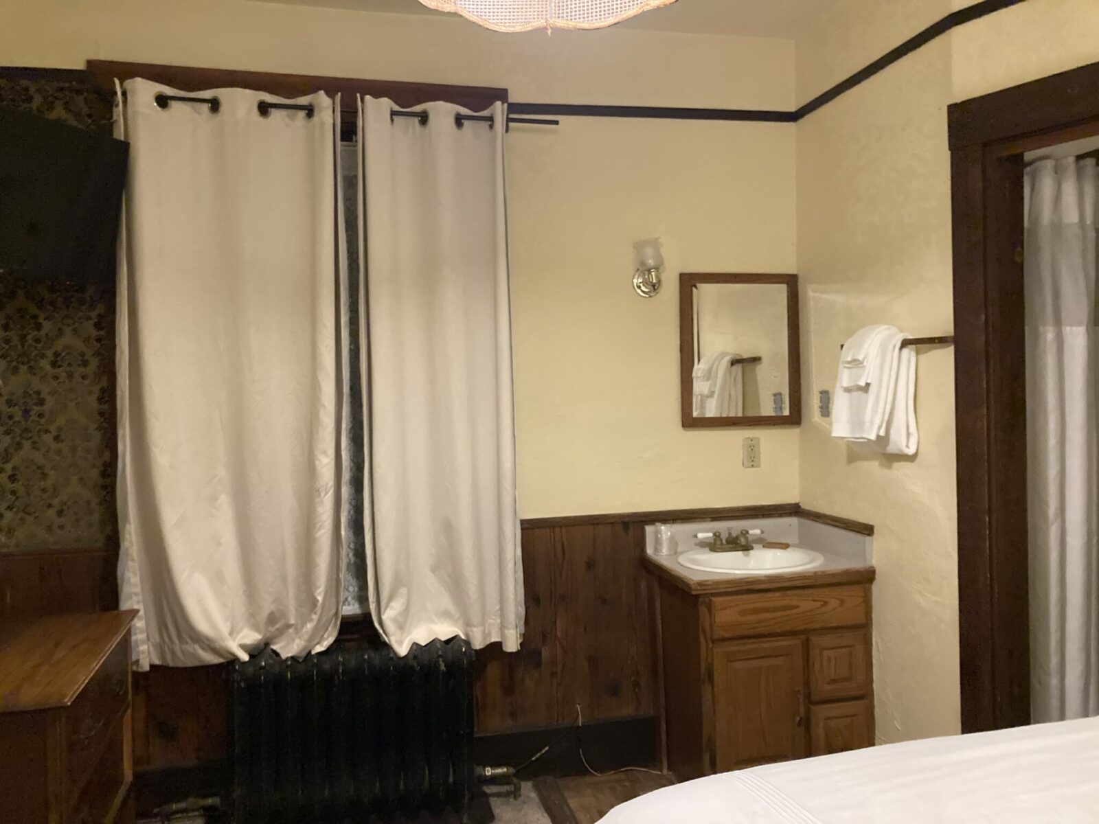 Part of a hotel room with curtains and a small sink