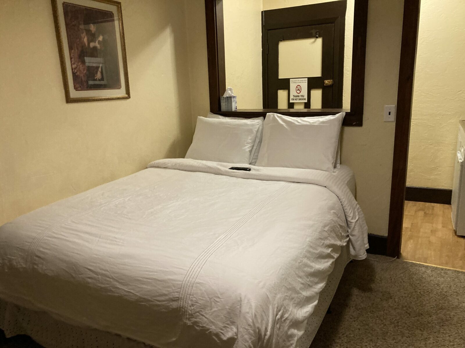 A queen size bed with white sheets in a historic hotel room.