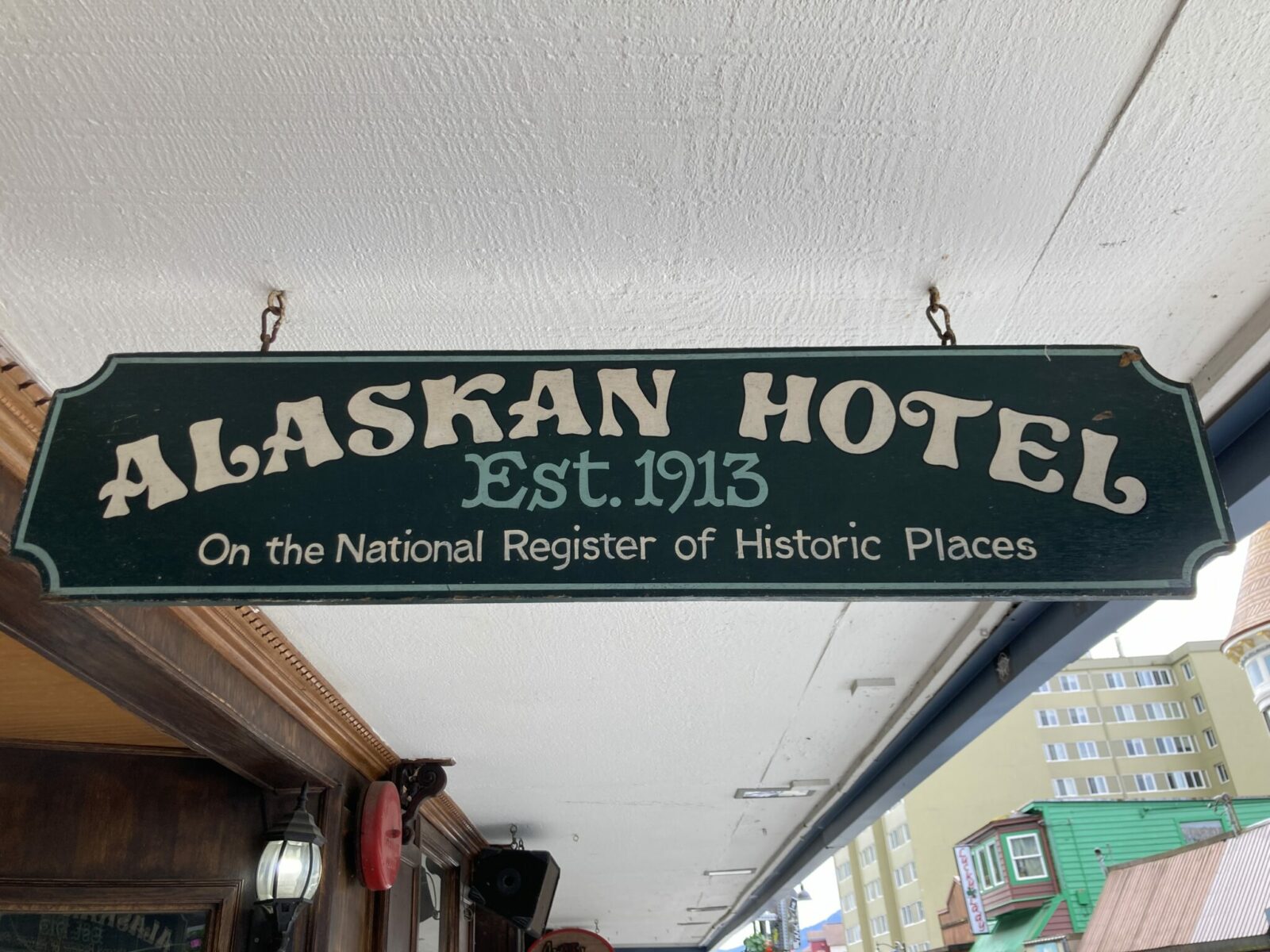 A sign hanging from an overhang that reads Alaskan Hotel est 1913. On the national register of historic places