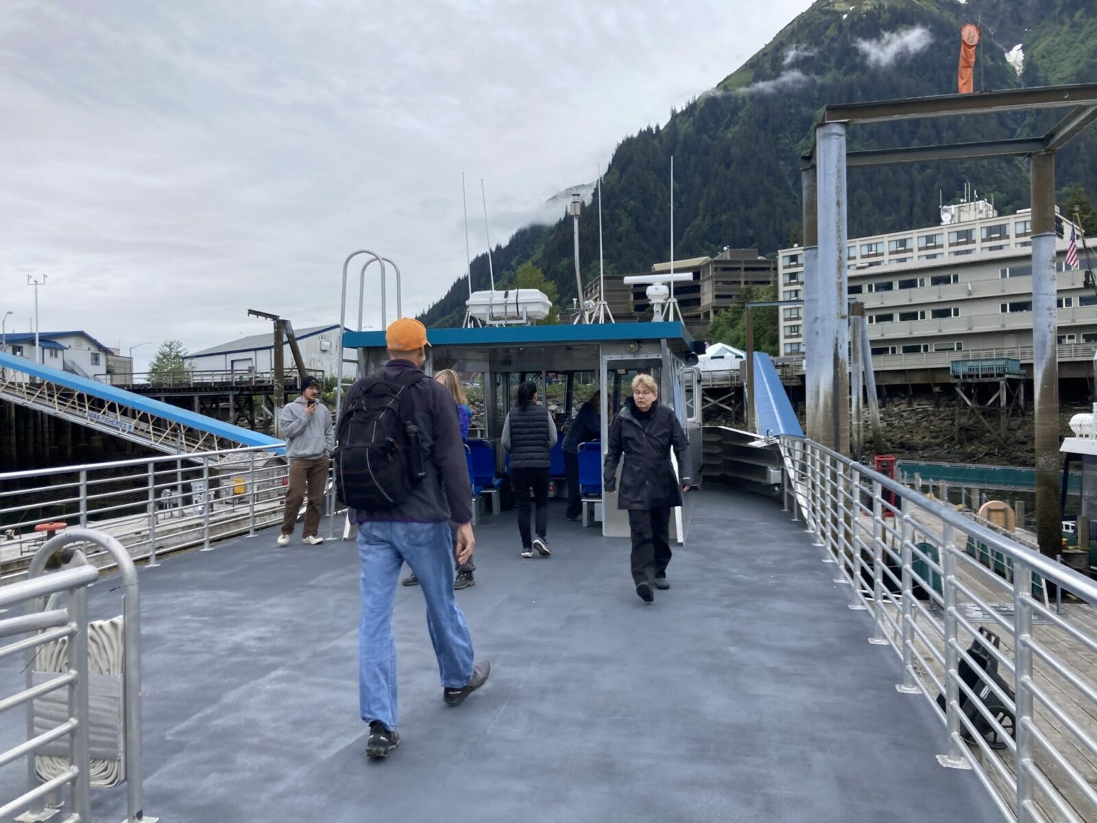 Several people in jackets on the upper deck of a tour boat docked in Juneau