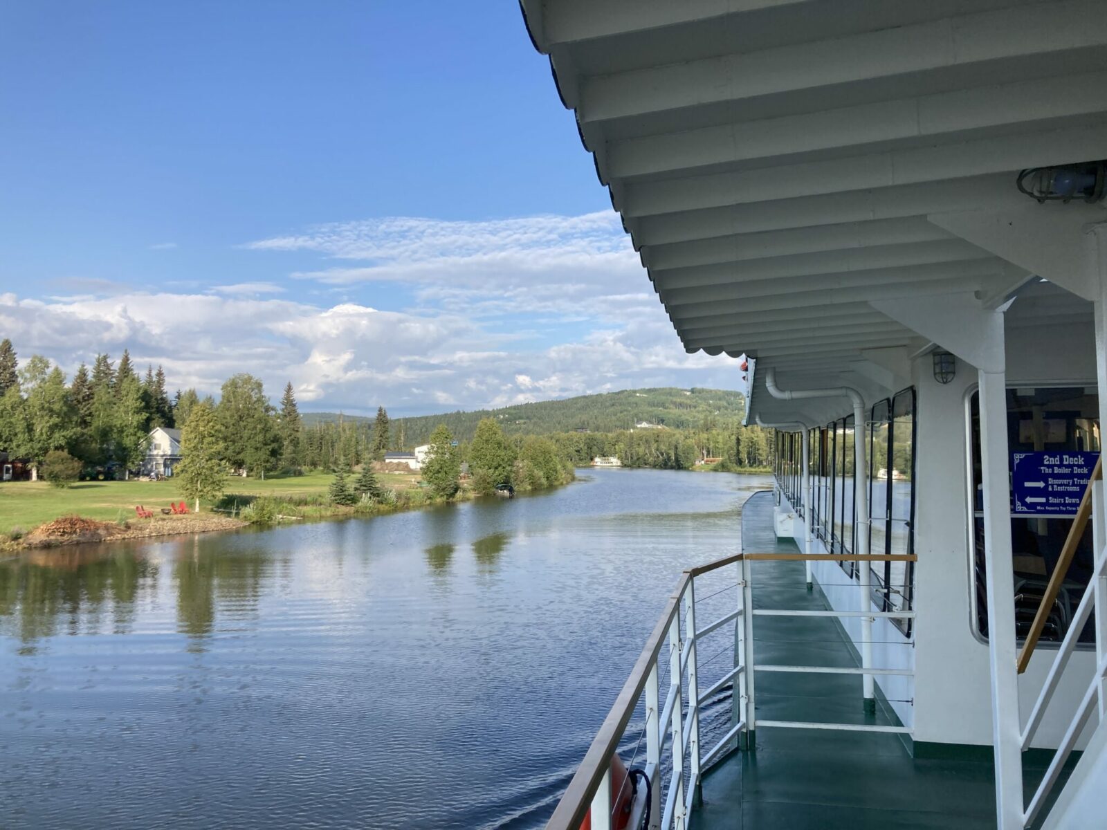 The deck of the Riverboat Discovery along the Chena River with homes and trees along the banks