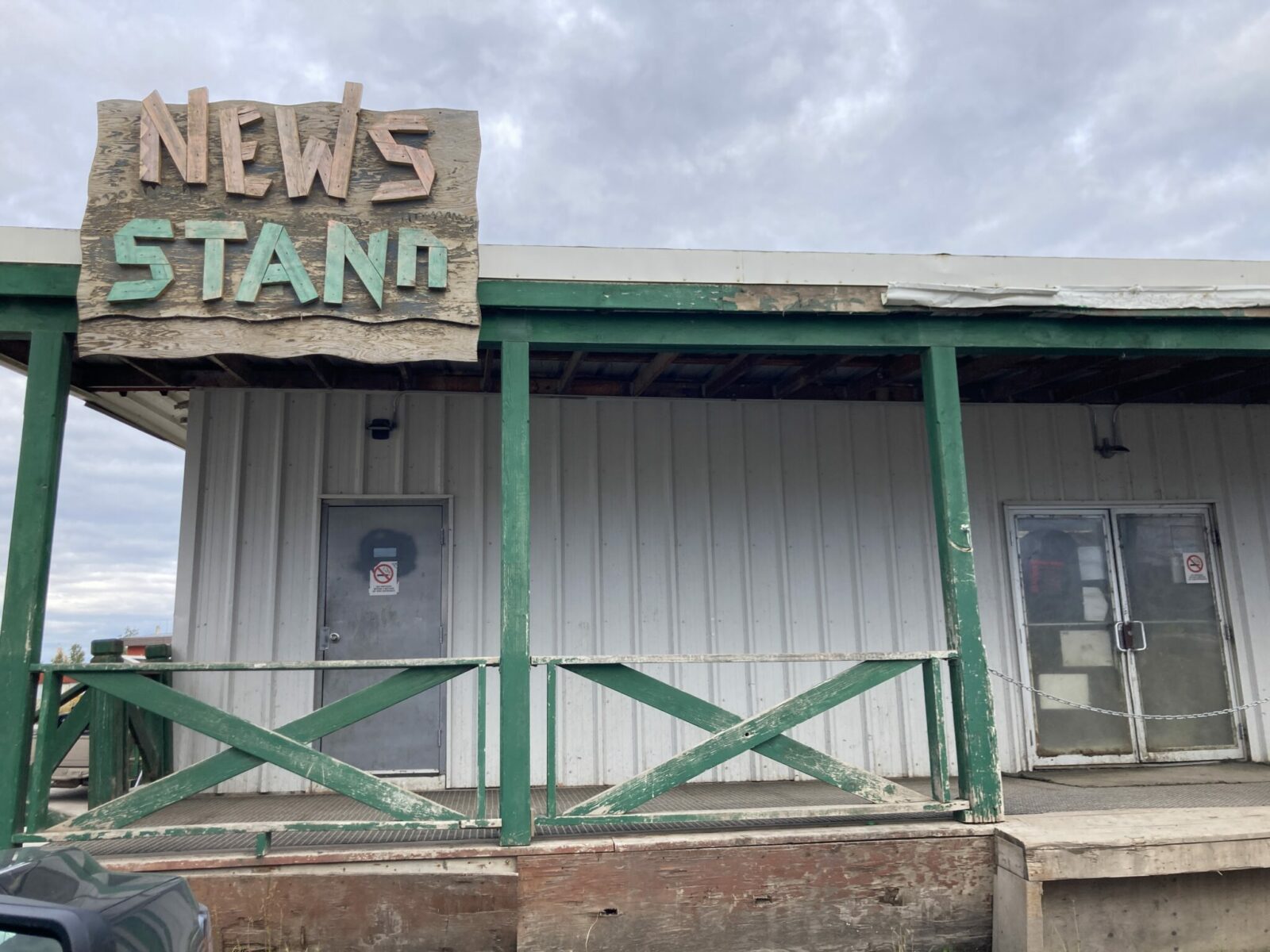 A run down building with a wooden sign that says news stand