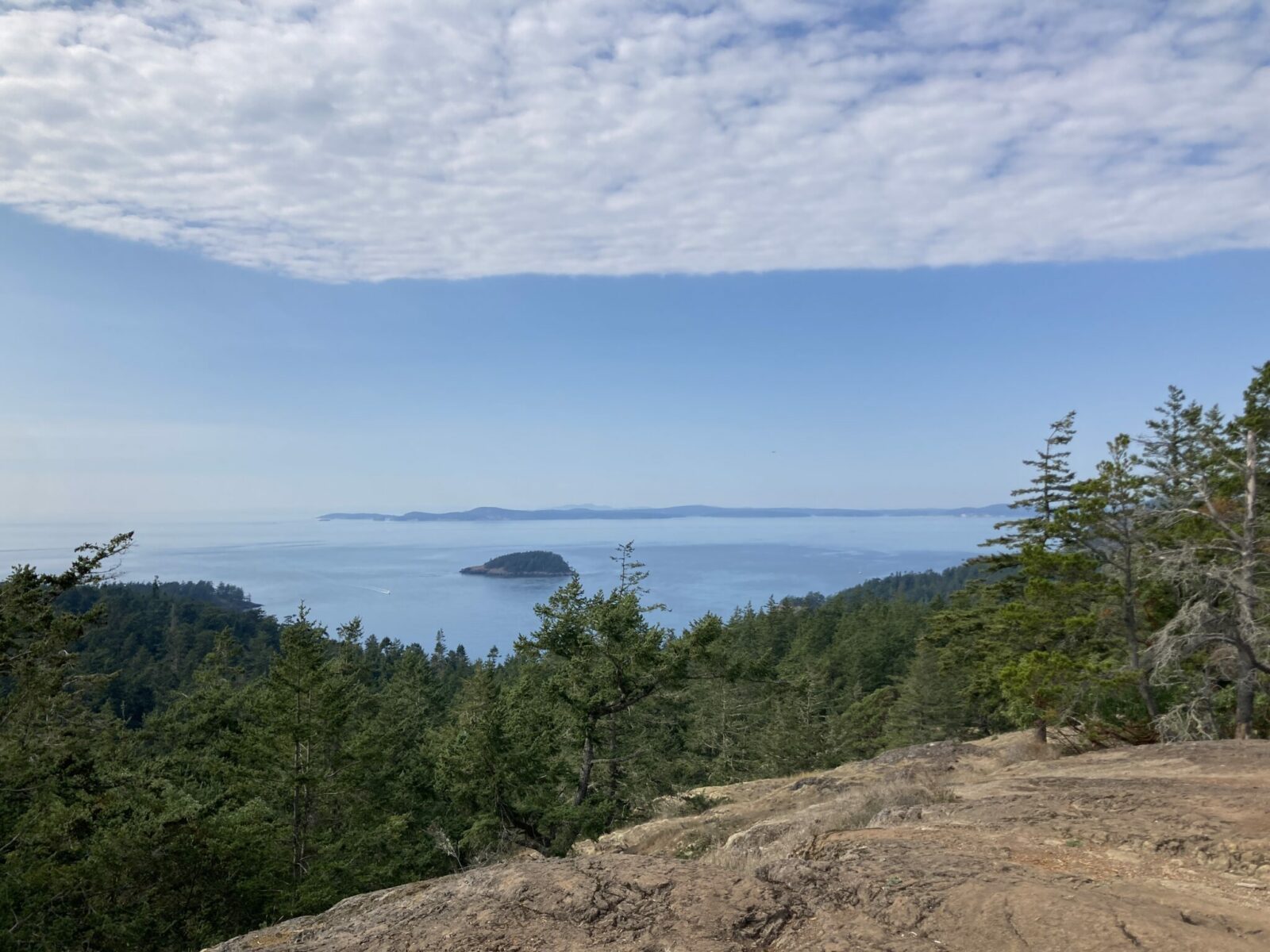 Distant ocean below with islands, rocks and forest in the foreground