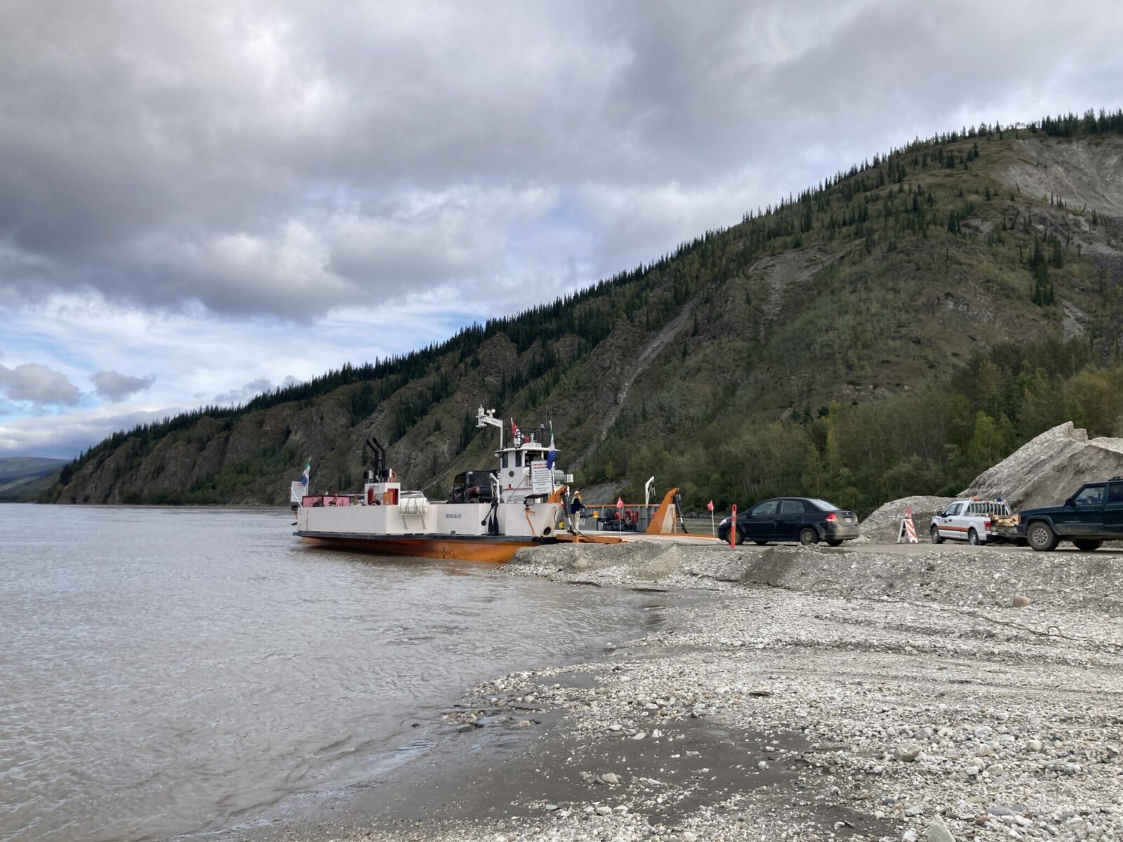 cars going onto a small river ferry with room for about six cars across the yukon river in dawson city