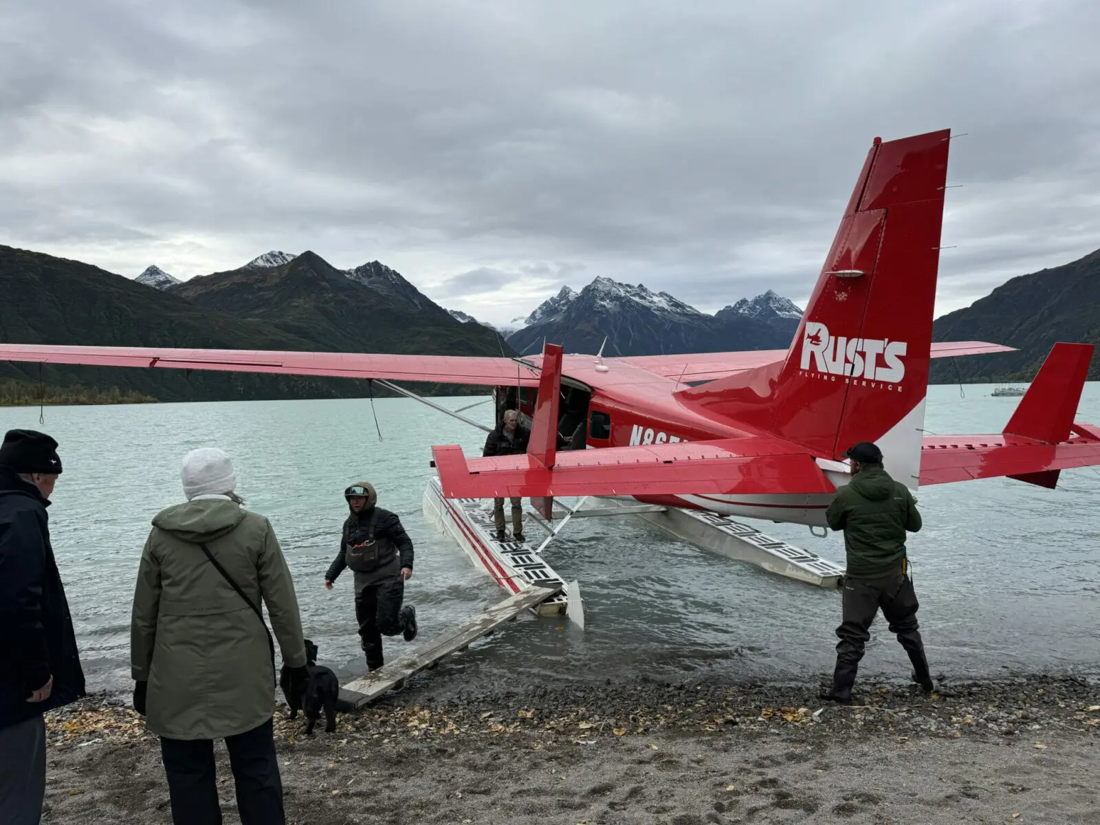 A red floatplane from Rust's Flying Service at the edge of Crescent Lake. Passengers are getting ready to board on the plank going to the float.