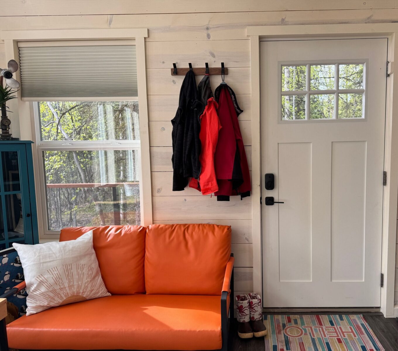 The entry door with a couch, boots and coats by the wall