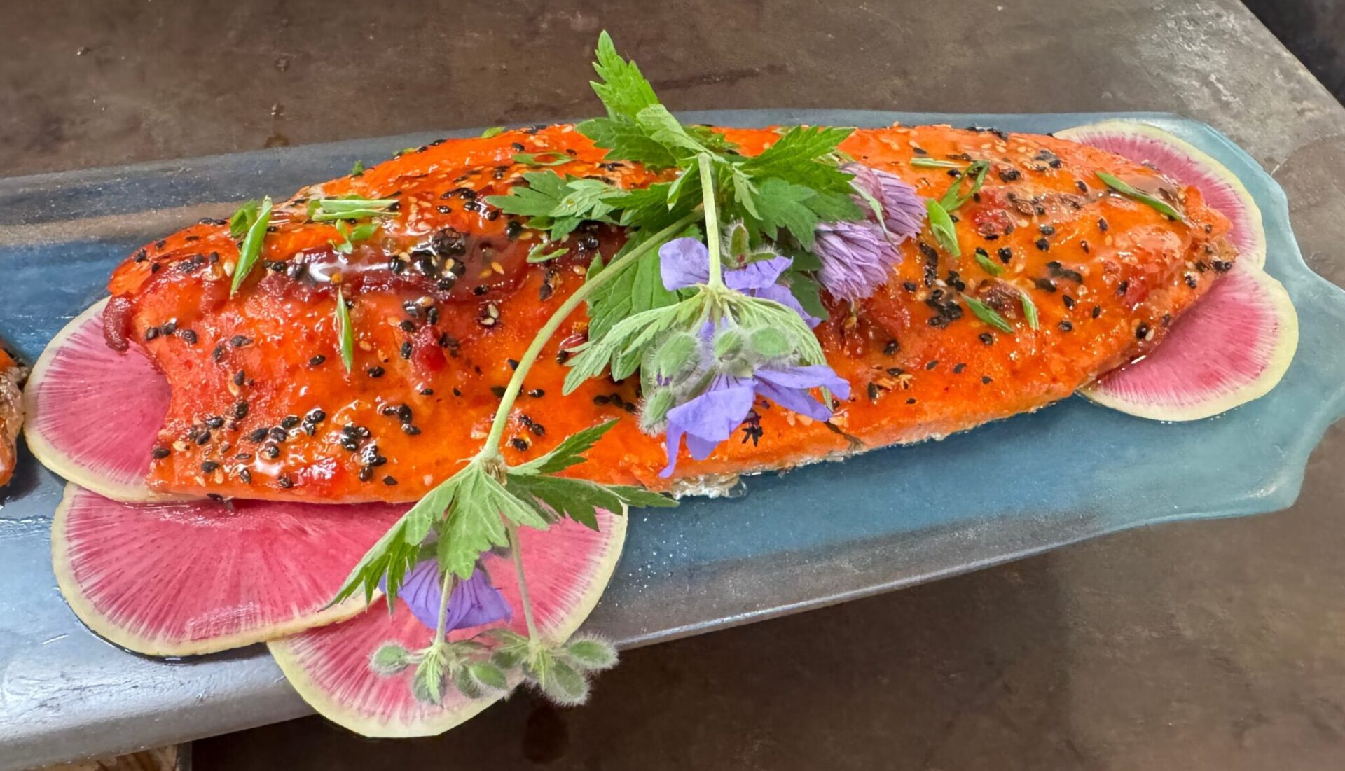 A filet of salmon with flowers and spices decorating it