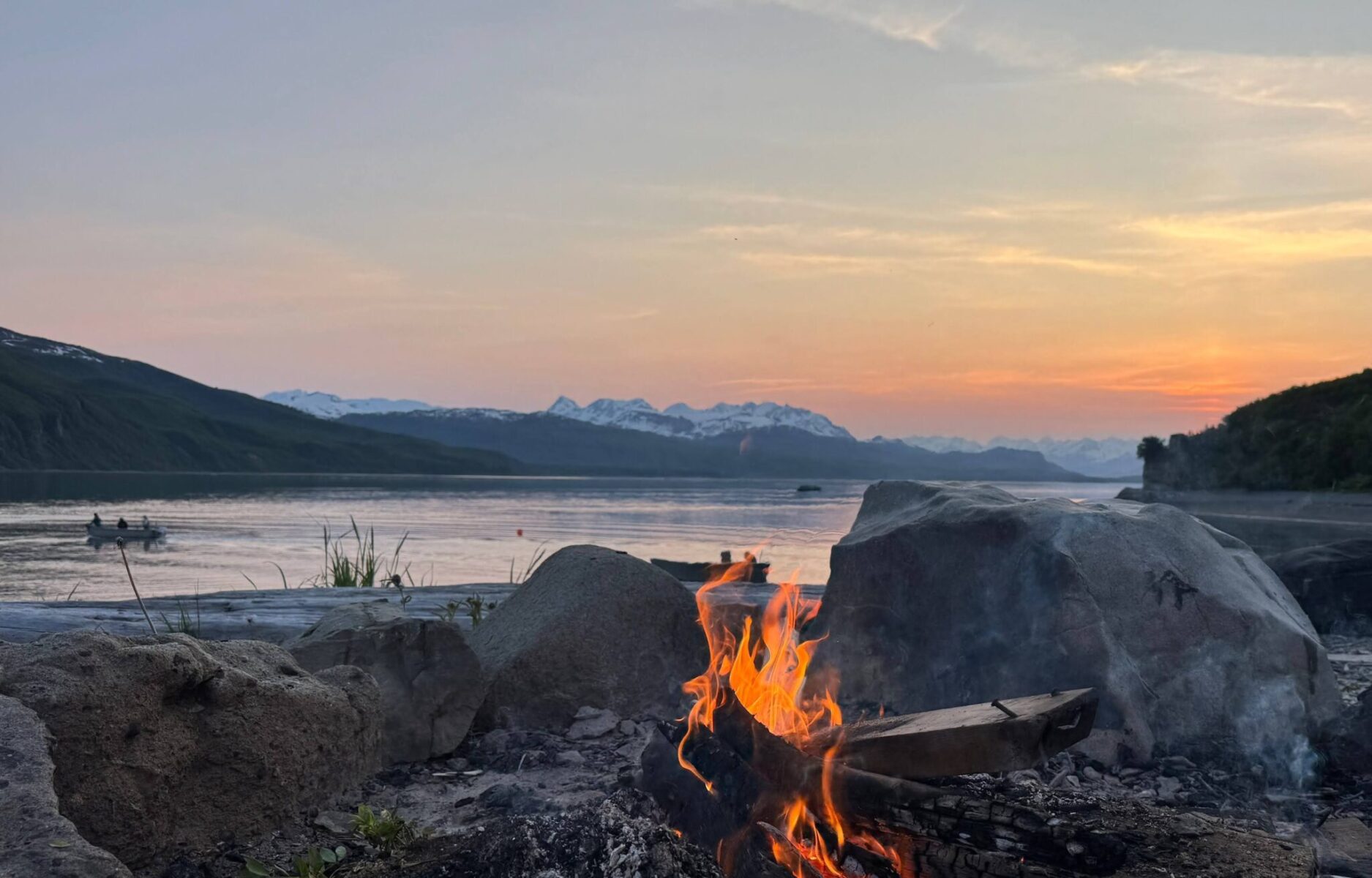 A fire at twilight with sunset behind distant mountains